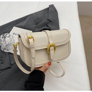 Detail of off-white leather shoulder bag featuring a gold horseshoe buckle and flap closure