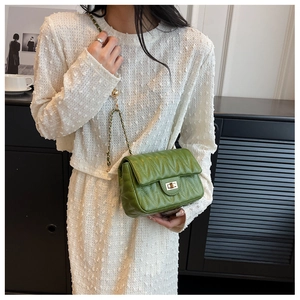 Detail of green quilted leather bag featuring a gold twist lock and chain strap