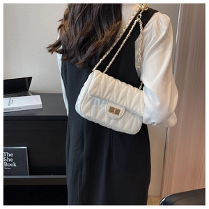 Detail of white quilted crossbody bag with gold chain strap on female model