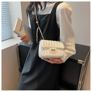 Detail of white quilted crossbody bag featuring a gold twist lock and chain strap