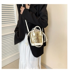 Detailed view of mini bucket bag featuring gold sequins and drawstring closure worn by model