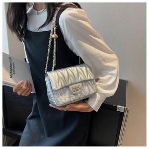 Close-up of silver quilted crossbody bag featuring a gold chain strap and turn-lock