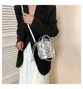 Silver sequin bucket bag with drawstring liner shown as a stylish crossbody fashion accessory