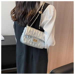 Detail of silver quilted chain bag featuring V-shaped stitching and golden twist lock