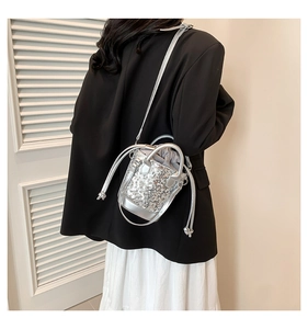 Silver sequin bucket bag worn with a black blazer and white pleated skirt