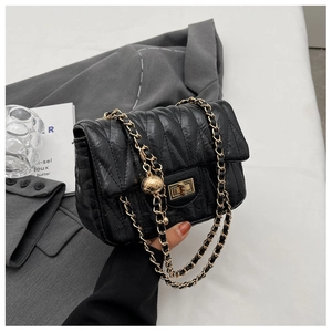 Close-up of quilted black leather crossbody bag with gold ball chain and twist lock