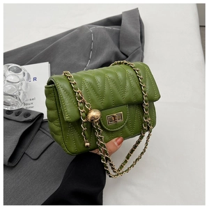 Detail of green quilted crossbody bag with golden chain and metallic ball charm