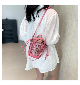 Detail of pink sequin bucket bag with drawstring closure and matching chain strap