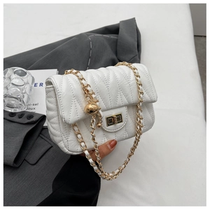 Detail of white quilted chain bag featuring gold metal turn-lock and decorative ball