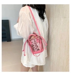 Detail of pink sequin bucket bag featuring drawstring closure and leather handle