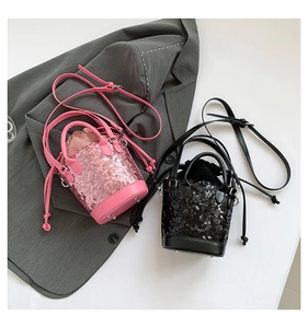 Top view of pink and black sequined bucket bags with chain straps on a grey suit