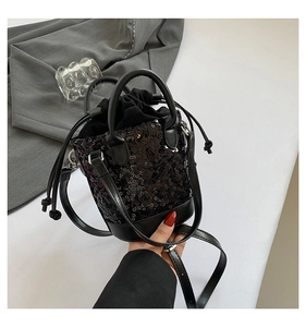 Detail of black sequined bucket bag featuring double handles and drawstring closure