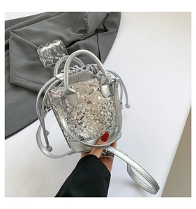 Detailed view of silver sequin bucket bag with drawstring closure and metal handle