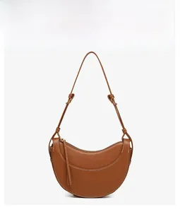 Close-up of caramel crescent bag featuring white contrast stitching and long fringe tassel