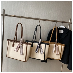 Three color-block tote bags with silk scarves displayed on minimalist metal hangers