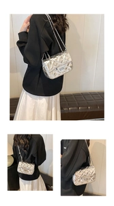 Detailed view of silver quilted chain bag featuring a metallic finish and turn-lock closure