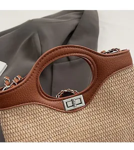 Close-up of woven straw bucket bag with brown leather trim and silver metal twist lock
