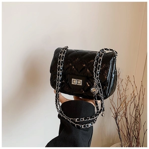 Detail of black quilted patent leather handbag with silver rectangular swivel lock and chain