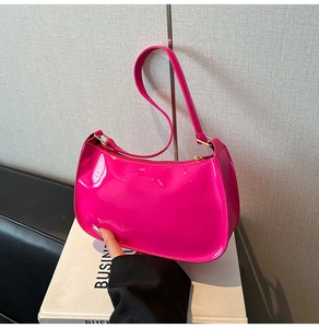 Detail of rose pink glossy patent leather shoulder bag with metallic buckle and hobo design