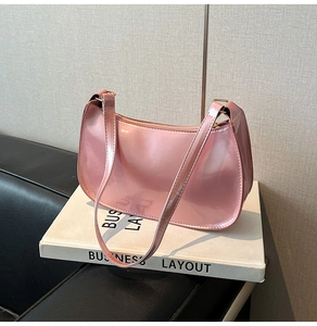Detailed view of pink patent leather underarm bag with glossy mirror finish on books