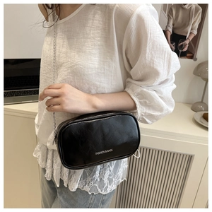 Detail of a black glossy leather crossbody bag with silver chain and FASHION & BAGS print
