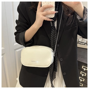 Selfie miroir montrant le mini sac bandoulière en cuir crème avec bandoulière chaîne