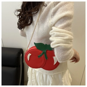 Detailed macro view of cherry-shaped crossbody bag with leaf accent and gold chain strap