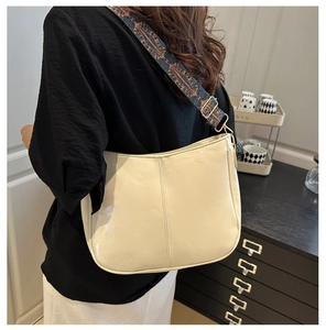 Close-up of cream crossbody bag featuring a bohemian style colorful patterned wide strap