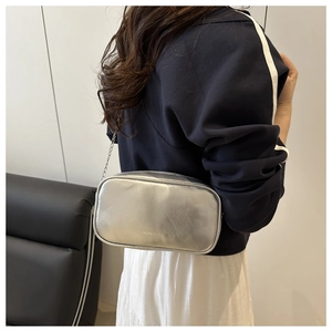 Détail du sac oreiller argenté métallisé avec bandoulière chaîne et texte sur modèle