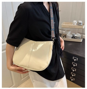 Close-up of beige patent leather saddle bag with vintage ethnic woven wide shoulder strap