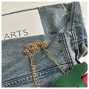 Detail of green leather cherry bag showing golden chain strap and fine stitching work