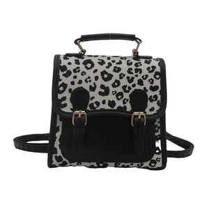Fashionable black and white leopard print backpack with faux leather trim and gold buckles