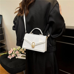 Minimalist white crossbody bag with golden oval lock and adjustable shoulder strap