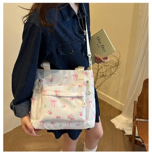 Detail of floral printed nylon tote bag showing multiple functional zipper pockets and straps