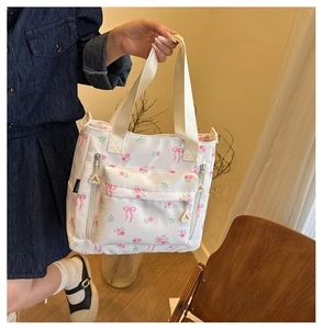 Detail of white tote bag with pink rose patterns and vertical zipper pockets