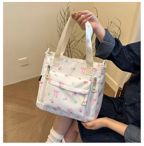 Detail of white tote bag with pink rose prints and multiple zipper pockets