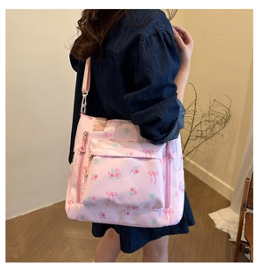 Detailed shot of pink floral tote bag with ribbon patterns and functional side zippers