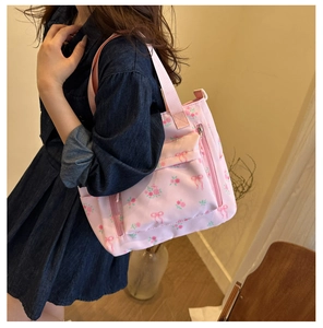 Close-up of pink floral tote bag with rose print and double straps in home setting