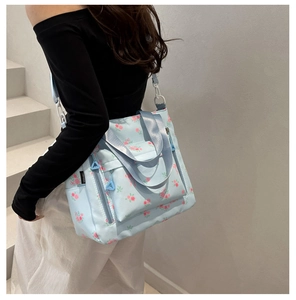 Detail of light blue floral tote bag showing side brand label and durable canvas texture
