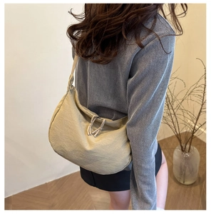 Detail of minimalist beige nylon crescent bag showing soft fabric texture and zipper closure