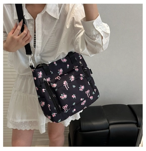 Detail view of floral tote bag with pink roses and bows on black nylon material