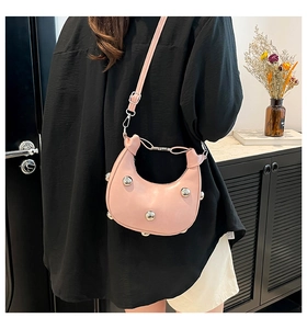 Detailed view of pink crescent moon bag with silver rivets worn by a model in casual style