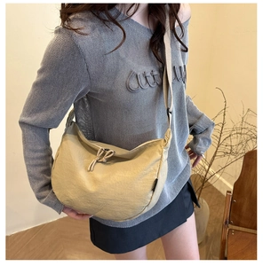 Detail of a beige crescent nylon crossbody bag with textured fabric and drawstring zip