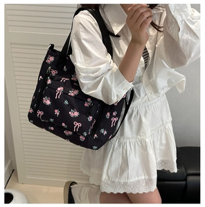 Detail of black floral tote bag with pink butterfly prints and front zipper pocket