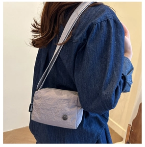 Detail showing pleated nylon texture and round metal M logo on the small square crossbody bag