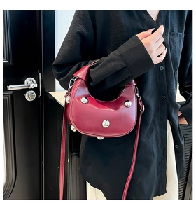 Detail of burgundy crescent bag with silver metallic studs and smooth leather texture