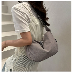 Detail of taupe crescent nylon tote bag with minimalist knot zipper and high-capacity design