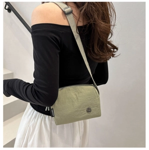 Détail d'un sac bandoulière vert olive avec sangle ajustable porté par un mannequin