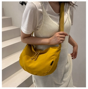Detail of ginger yellow nylon crescent bag with drawstrings and wide woven strap