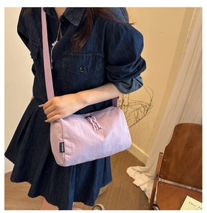 Detail of light purple nylon crossbody bag with wide strap on a model wearing denim